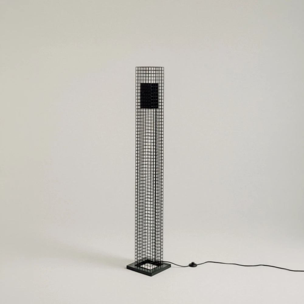 Full-length studio view of the black Ami Floor Lamp by Garnier Pingree, showing its slender grid column, square base and trailing cable.